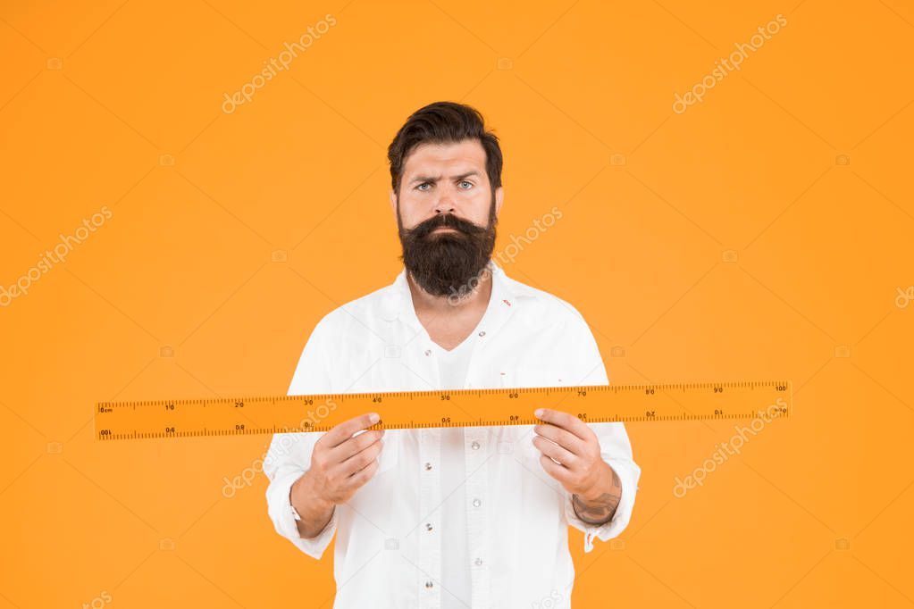 Teaching geometry at school. School teacher holding measuring instrument on orange background. Bearded man preparing ruler for school lesson. Welcome back to school