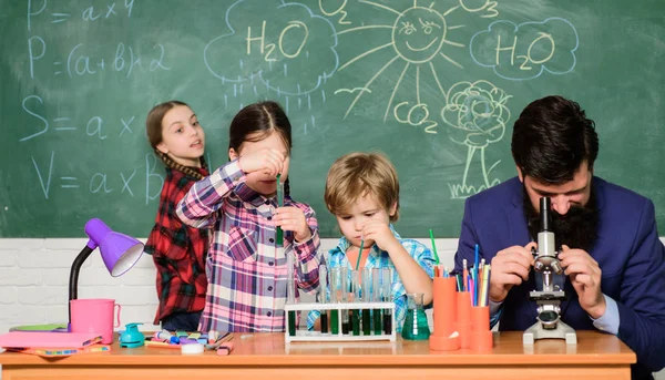 Profesor barbudo y alumnos con tubos de ensayo en clase. Observa la reacción. La ciencia es siempre la solución. Experimento de química escolar. Explicando química a los niños. Fascinante lección de química — Foto de Stock