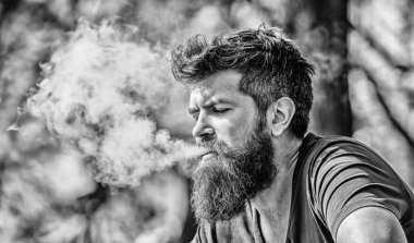 Uzun sakallı adam sigara içmekten rahatlamış. Sakallı adam duman üfledi. Kokulu duman bulutları. Stres atma konsepti. Tüttüren sakallı adam. Elektronik sigara içiyorum. Sigara içme aygıtı