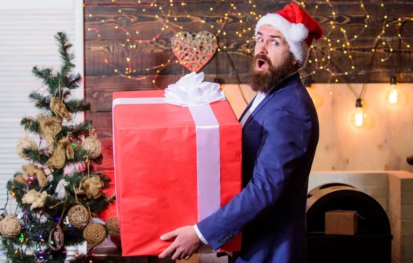 Legnagyobb ajándék karácsonyra. Ünnepeld a karácsonyt óriás ajándékokat. Nagy göngyös doboz szalaggal. Nagy meglepetés. Készítsünk nagy meglepetésszerű ajándékot. Ember Mikulás kalap szállítására nagy ajándékdobozban. Méretes ügyek — Stock Fotó