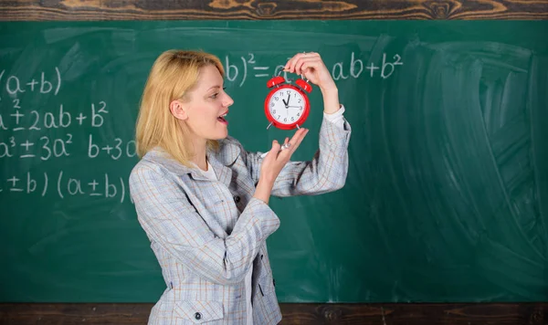 Bem-vindos ao ano lectivo. Educador experiente começa a lição. Ela preocupa-se com a disciplina. Que horas são? Professora segura o despertador. Menina formal usar professor da escola. Tempo de estudo — Fotografia de Stock