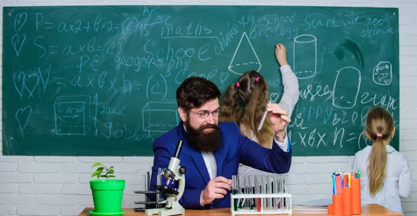 Biology plays role in understanding of complex forms of life. Explaining biology to children. Man bearded teacher work with microscope and test tubes in biology classroom. School teacher of biology