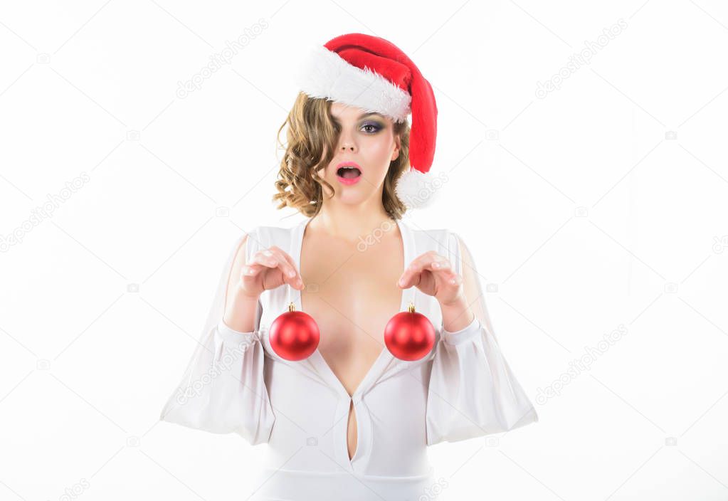 Girl santa hat hold balls decorative ornament in front of breasts. Christmas balls symbol implant female breasts. Christmas miracle concept. Breasts augmentation as gift for new year. Plastic surgery