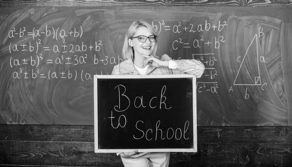 Começa o ano lectivo. Principais maneiras de receber os alunos de volta à escola. A professora tem inscrições de quadro-negro na escola. É hora da escola novamente. Professor da escola feliz em acolher alunos — Fotografia de Stock