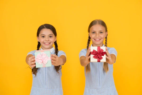Ossza meg boldogságát. Ünnep ünnepe. Megosztása ajándékokat. Lányok nyitó ajándékok sárga háttér. Osztálytársaival, amely ajándékok dobozok. Oktatási program a tehetséges gyerekeknek. Iskolai szünnap. Neveltetés nagylelkűség — Stock Fotó