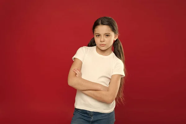 Elegante e confiante. Criança pequena e gira. Menina da moda no fundo vermelho. Criança menina adorável em estilo casual. Criança com cabelo longo e elegante. Pequena fashionista. Aparência de moda de modelo pequeno — Fotografia de Stock