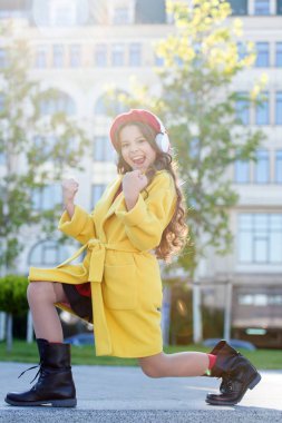 Harika bir ses. Kulaklık takan şehir geçmişi olan bir kız. Stereo sesi. Sonbahar çocuk kıyafetleri müziğin tadını çıkarıyor. Müzik dinleyen küçük kız en sevdiği şarkının tadını çıkarıyor. Sadece iyi titreşimler.