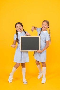 Okul haberleri. Gerçek bilgi. Küçük kızlar yazı yüzeyi sarı arka plan tutun. Bilgi yazmak için çocuklar ve tebeşir tahtası. Bilgi için boş tahta. Taze okul bilgileri kopyalama alanı