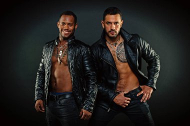 Erkekler gülümseyen yüzler kıl ile üzerinde. Deri erkek giyim kavramı. Maço kas torsolar ile deri ceketler, koyu arka plan çekici görünüyorsun. Seksi kas torsolar erkeklerle vahşice bak