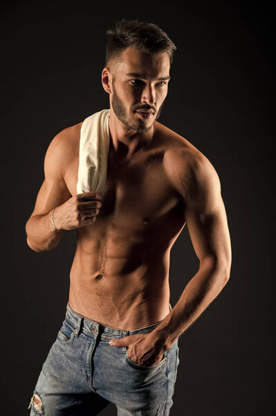Undress for you. Athlete with sexy muscular body on confident face. Man muscular torso tense muscles veins hand in pocket denim pants. Macho muscular chest looks attractive black background