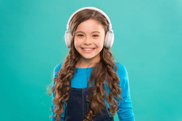 Modern und stilvoll. fröhliches kleines Kind, das moderne Musik auf blauem Hintergrund genießt. kleines Mädchen mit stylischem Kopfhörer, das moderne Lieder hört. Nutzung moderner Technologie für Vergnügen und Studium — Stockfoto