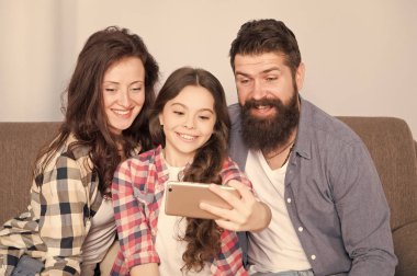 Evde mutlu bir aile. Küçük kız anne ve babasıyla smartphone kullanın. Aile mutlu ruh hali ile. Mutlu aile selfie. Sakallı erkek ve kadın kızı çocuk ile. Mutlu bir aile. Parlak anlar yakalama