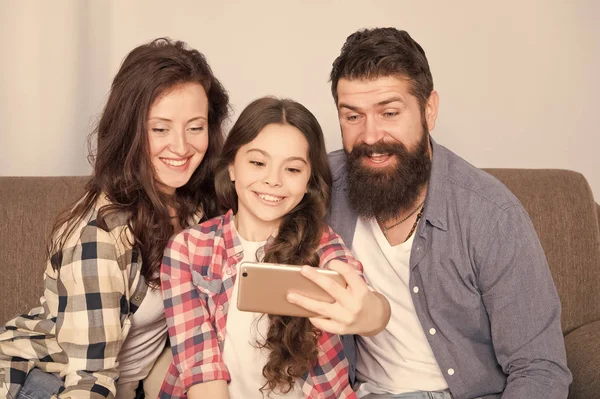 Evde mutlu bir aile. Küçük kız anne ve babasıyla smartphone kullanın. Aile mutlu ruh hali ile. Mutlu aile selfie. Sakallı erkek ve kadın kızı çocuk ile. Mutlu bir aile. Parlak anlar yakalama — Stok fotoğraf