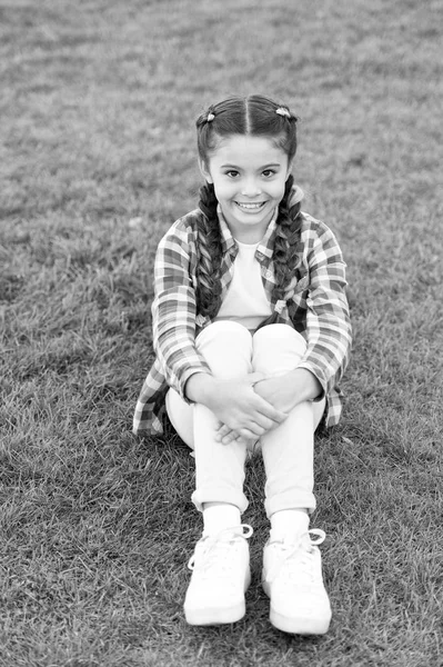 Agradable paseo por el parque. Sonrisa y alegría. Peinado de moda para niños. Niña pequeño niño con trenzas de moda peinado. Una sonrisa encantadora. Tendencia de moda. Salón y cuidado del cabello. Chica sonrisa cara al aire libre — Foto de Stock