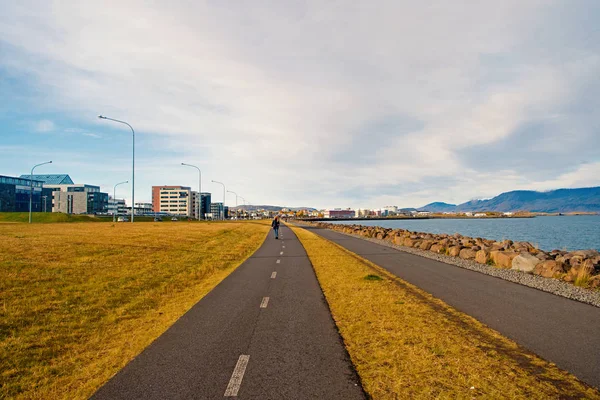 Reykjavik, Iceland - October 12, 2017: travel road along sea coast. Country road on cloudy sky. Miles of travel. Promenade road. The road will rise to meet the one who walks it — Stock Photo, Image