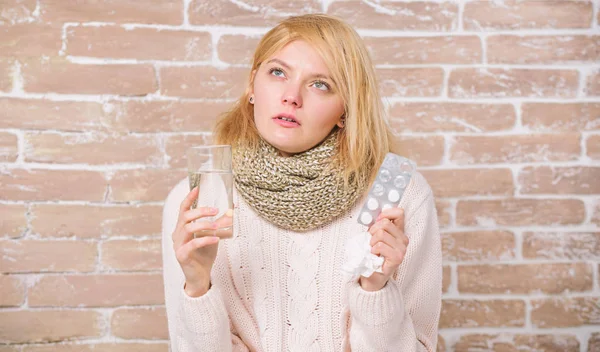 Algo de alivio del frío. Mujer enferma que trata los síntomas causados por el resfriado o la gripe. Mujer malsana sosteniendo pastillas y vaso de agua. Linda chica enferma tomando píldoras contra el frío. Medicamentos y aumento de la ingesta de líquidos —  Fotos de Stock