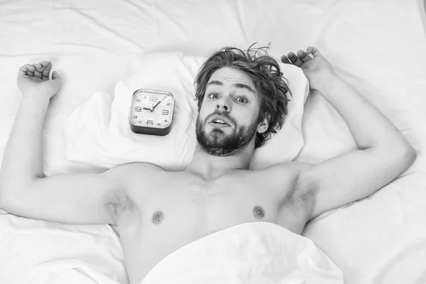 Un hombre guapo bostezando y estirando los brazos. Un joven despertando en la cama y estirando los brazos. Despierta por la mañana. . — Foto de Stock