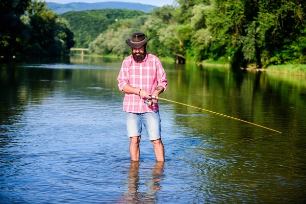 Mature bearded man with fish on rod. big game fishing. relax on nature. successful fisherman in lake water. hipster fishing with spoon-bait. fly fish hobby. Summer fishery activity. real professional — Stock Photo, Image