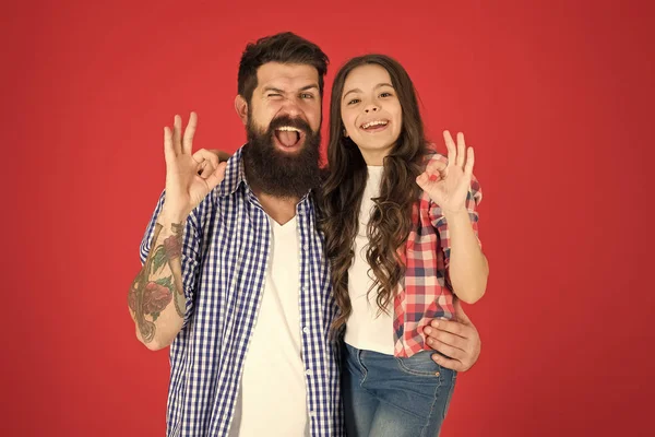 Father and daughter hug on red background. Child and father best friends. Parenthood goals. Happy childhood. Fathers day concept. Lovely bearded dad and cute kid. Cheerful family. Happy fathers day