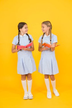 Samimi ilgi. Okul kütüphanesi. Okul için eğitim kitapları. Kitap okuyorum. Okumak ve yeniden anlatmak. Kitapları sarı arka planda tutan küçük çocuklar. Ansiklopedi veya çocuk kitapları ile küçük kızlar