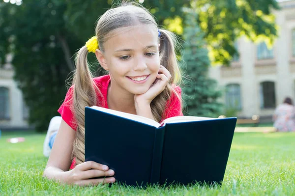 Školka četla příběhy, když odpočíváš zelený trávník. Roztomilý žák si rád čte. Školní čas. Zajímavé příběhy pro děti. Studuji s potěšením. Čas na velké příběhy. Malé dítě čteš knížku venku — Stock fotografie