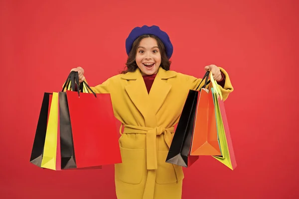 Fashionista adore shopping. Customer satisfaction. Prime time buy spring clothing. Obsessed with shopping. Girl cute kid hold shopping bags red background. Get discount shopping on birthday holiday — Stock Photo, Image