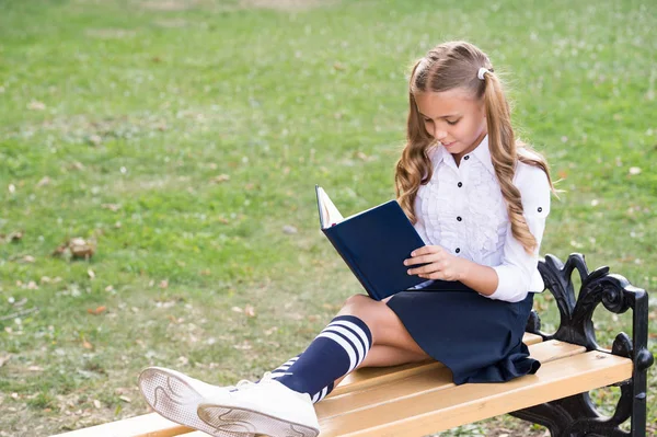 Dags att studera. Studerar på skolgården. Smart skolflicka. Studerande förtjusande barn i formell uniform avkopplande utomhus. Läsbok för skolflickor. Ett litet geni. Skolflicka avkopplande sitta bänk med bok — Stockfoto