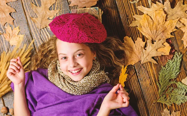 Sonbahar moda aksesuar kavramı. Moda trend sonbahar sezonu. Kız yatıyordu ahşap arka plan yaprakları yukarıdan düşmüş. Aksesuar moda ayrıntı ördü. Küçük çocuk kız parlak yumuşak örme şapka bere moda