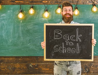 Lise konsepti. Gözlüklü öğretmen okula geri başlık ile tahta tutar. Neşeli gülen yüzünde sakallı ve bıyıklı adam öğrencileri karşılıyor, backgroun üzerinde tebeşir