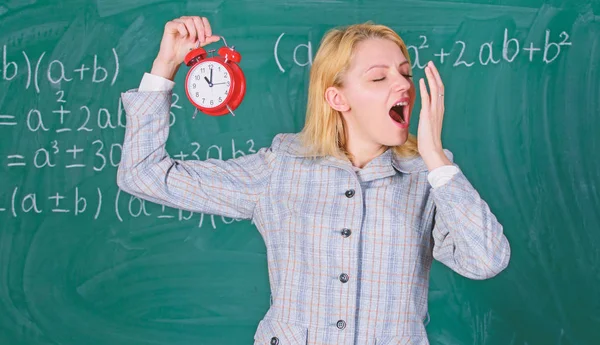 Bienvenue professeur année scolaire. Un éducateur expérimenté commence la leçon. Elle se soucie de discipline. La maîtresse tient le réveil. Fille formel porter professeur de l'école. Quelle heure est il ? Calendrier des leçons — Photo