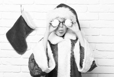 Dekoratif Noel veya Noel çorap veya marshmallow kafa yakınındaki beyaz tuğla duvar arka planda tutan önyükleme ile kırmızı kazak ve yeni yıl şapkalı gözlüklü genç sevimli Noel Baba çocuk