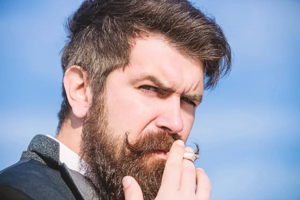 Człowiek z wąsami brodą trzymać papierosa. Brodaty Hipster palenia papierosów niebo tle. Facet papierosów cieszyć się wpływem nikotyny. Papierosy pomagają nam wszystko od nudy do zarządzania gniewem — Zdjęcie stockowe