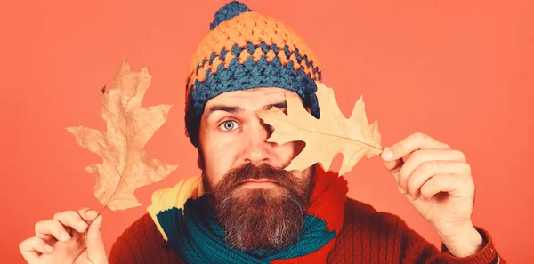 Guy with calm face wears warm hat on orange background