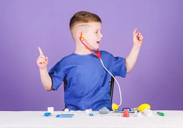 Concepto de medicina. Salud. Examen médico. Educación médica. Juega a juego. Niño lindo niño futuro médico carrera. Vida sana. Pequeño doctor sentado mesa con estetoscopio y herramientas médicas — Foto de Stock