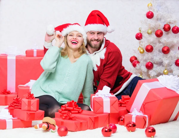 周りに幸せを広めるのは簡単です。幸せな家族はクリスマスを祝います。クリスマスギフトのコンセプト。愛のカップルはクリスマスのお祝いを楽しむ。カップルはサンタクロースクリスマスツリーの背景として帽子を着用 — ストック写真