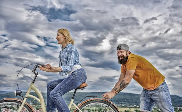 Mujer paseos bicicleta cielo fondo. Empuja y promueve. Impulso a moverse. El hombre empuja a la chica en bicicleta. El apoyo ayuda a creer en ti mismo. Siente el impulso de empezar a moverse. Chica en bicicleta, mientras que el hombre la apoya — Foto de Stock