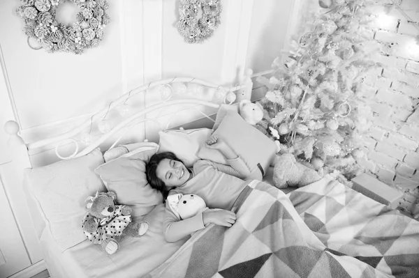 Концепция сочельника. Ребенок ждет Рождества в спальне. Ребенок лежал в постели расслабляясь. Дом лучшее место в мире. Девочка маленькая девочка расслабляется на кровати светлый интерьер с рождественскими украшениями — стоковое фото