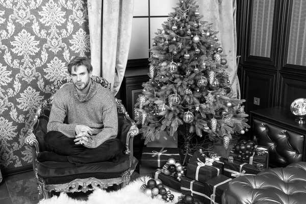 Hombre sentarse en sillón rojo en el árbol de Navidad — Foto de Stock