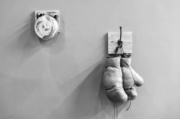 Final sparring. Vintage boxing gloves hang on hook wall background. Boxing gloves and ring bell. Boxing career famous sportsman. Museum of box sport. Box exhibition retro attributes. Boxing school