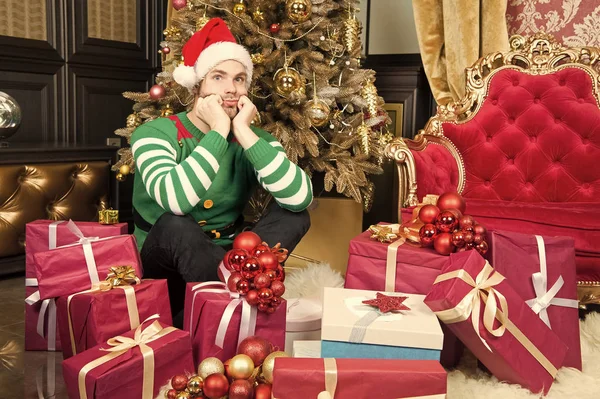 Man with present boxes at christmas tree. Man prepare present packs on new year eve. Man in santa costume celebrate new year. Santa stops here