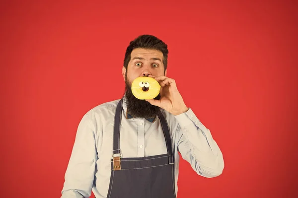 Voeding en gezonde voeding. Baker eten donut. Chef-kok man in café. Calorie. Het gevoel van honger. Bebaarde baker. Bebaarde man in schort. Baker greep donut. Grappige hipster. Professionele bakker. Zoete stemming — Stockfoto