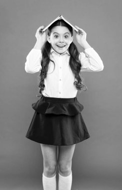 Bilginin pekiştirilmesi. Turuncu arka planda baş kitap tutan sevimli küçük kız. Sevimli küçük çocuk kitap bilgisi alıyor. Kapsamlı bilgi. Bilgi günü veya 1 Eylül