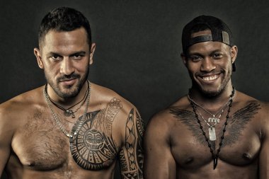Afrika insan ve dövmeli beyaz adam gülümseyen modelleri moda. Siyah arka plan üzerine vücut geliştiriciler. Sporcular ile seksi torsolar, vücut bakımı ve fitness kavramı. Moda modelleri moda aksesuarları