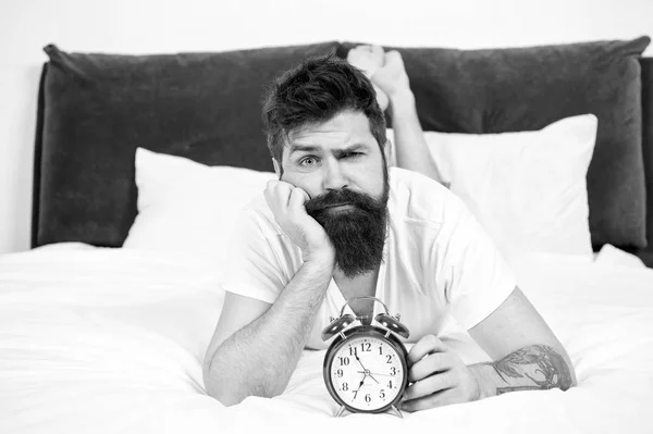 Mi sento esausta. stanco hipster uomo barbuto con sveglia. brutale uomo assonnato in camera da letto. gestione del tempo. maschio maturo con barba in pigiama sul letto. addormentato e sveglio. energia e stanchezza — Foto Stock