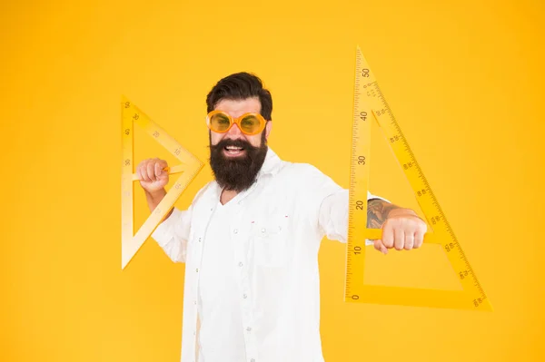 Os triângulos só têm três lados. Professor de escola ou estudante universitário sorrindo com triângulos geométricos para aula de geometria. Feliz hipster segurando triângulos no fundo amarelo. Lição em triângulos — Fotografia de Stock