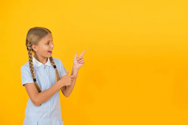 그냥 이것을 봐. 노란색 배경 복사 공간에 손가락을 가리키는 행복 한 어린 여학생. 학교로 돌아갑니다. 주의 개념입니다. 광고 모델입니다. 여학생 발표 학교 제품입니다. 긍정적 인 아이 — 스톡 사진