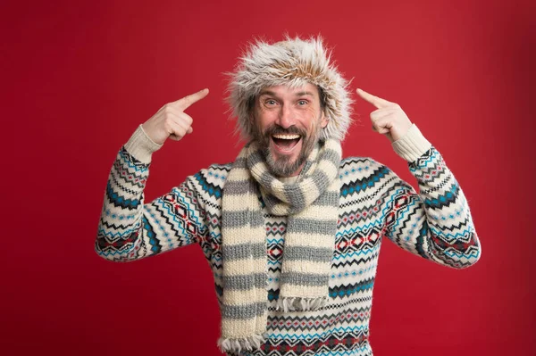 Het dragen van een aantal belangrijke winter accessoires. Bearded Man in trui en sjaal wijzend naar hoed. Een winter ensemble beschermt hem tegen kou. Volwassen fashion model in koud weer stijl. Winter garderobe voor man — Stockfoto