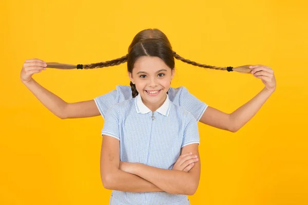 Spiel mit Zöpfen. Haarmode Schönheit. Kinderglück. kleine Mädchen in Schuluniform. Retro-Look. Kinder im Vintage-Stil. Alte Schule. Kindermode. glückliche Freunde auf gelbem Hintergrund — Stockfoto