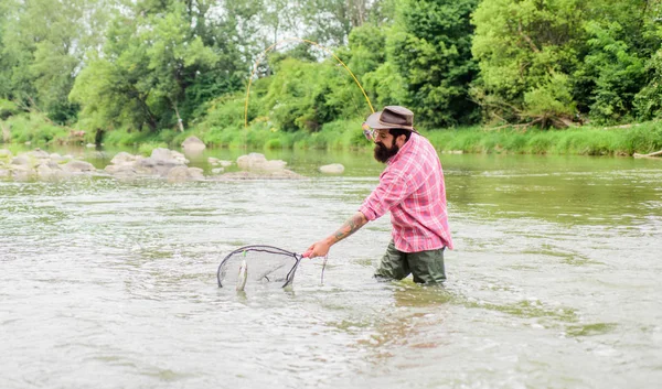 If fish regularly you know how rewarding and soothing fishing is. Fishing is an astonishing accessible recreational outdoor sport. Fishing hobby. Bearded brutal fisher catching trout fish with net