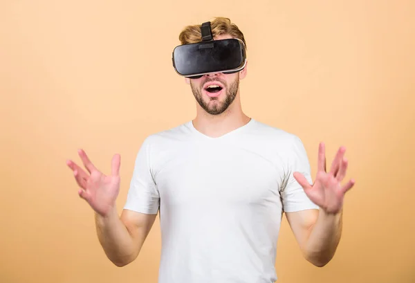 Entertainment and education. Virtual communication. Virtual simulation. VR for gaming. Man play game in VR glasses. Explore cyber space. Man hipster with virtual reality headset on peach background